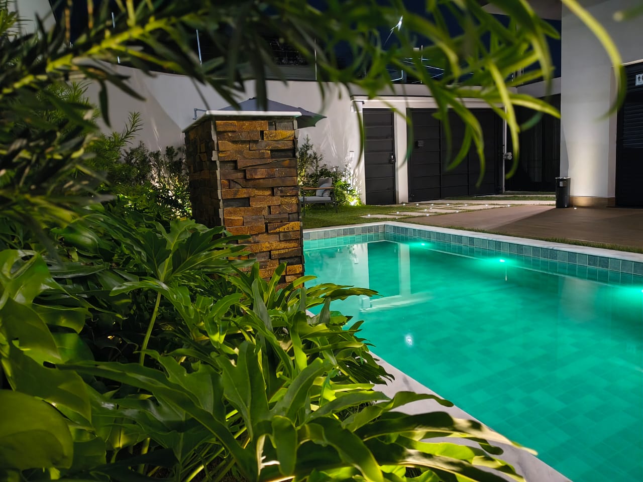 Piscina à noite vista entre a vegetação