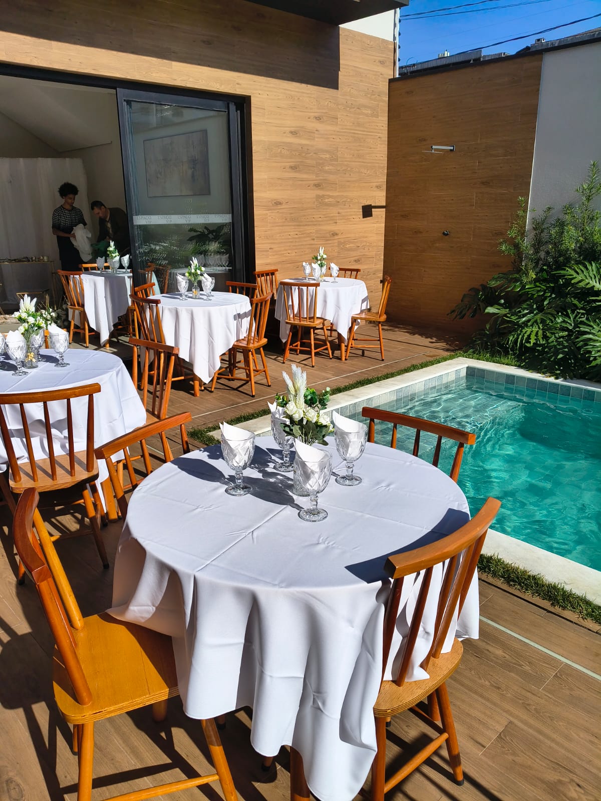 Mesas postas à beira da piscina para almoço ao ar livre
